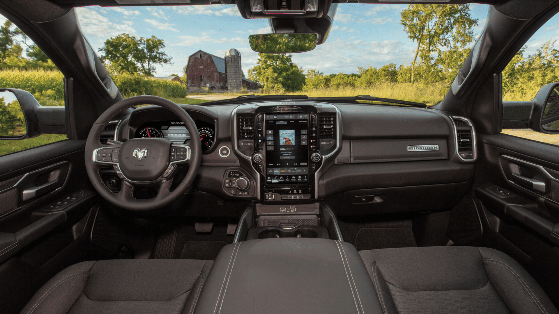 2026 Ram 1500 Hemi interior with touchscreen display, steering wheel, and barn view outside.