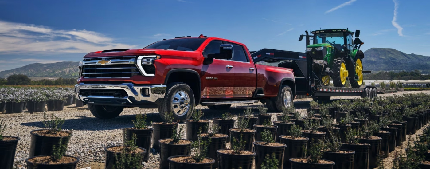 Red 2025 Chevy Silverado 3500 HD towing a tractor