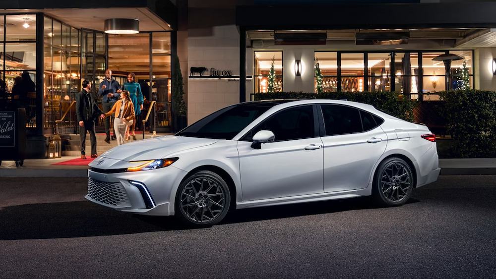 A silver 2026 Toyota Camry sedan parked in front of a restaurant at night