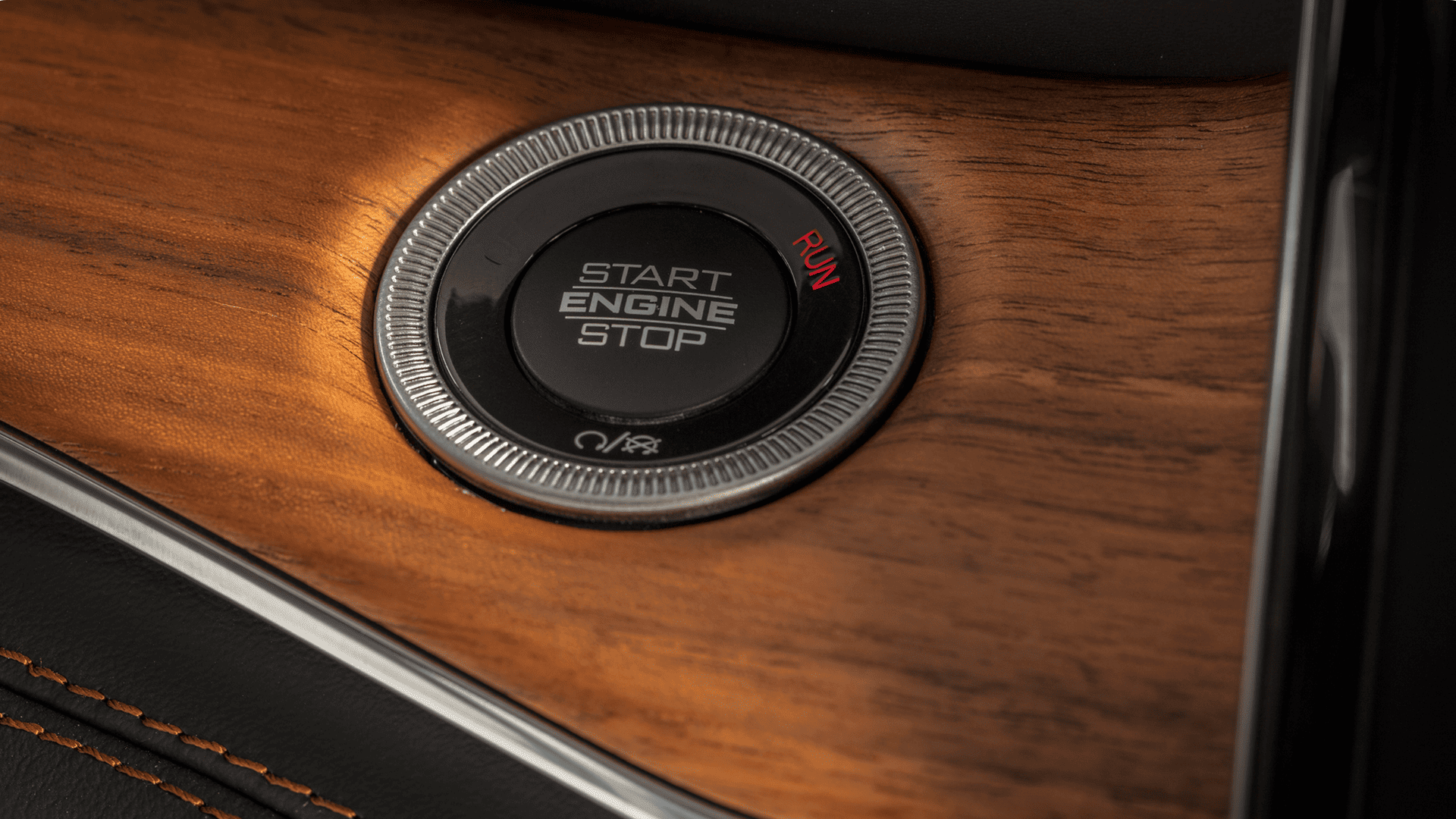 Detailed shot of the Grand Cherokee&rsquo;s push-to-start engine button on a premium wood-trim console.