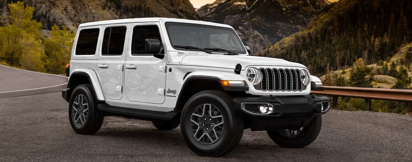 White 2025 Jeep Wrangler Sport parked with a mountain view