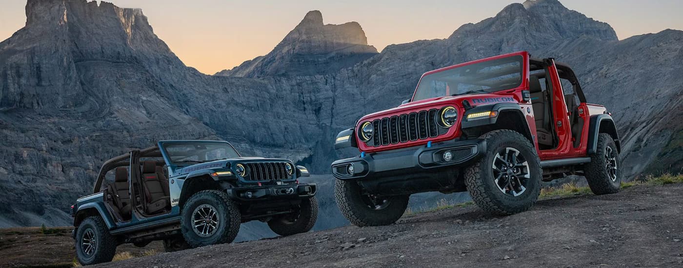A red and a grey 2025 Jeep Wrangler Rubicon parked off-road