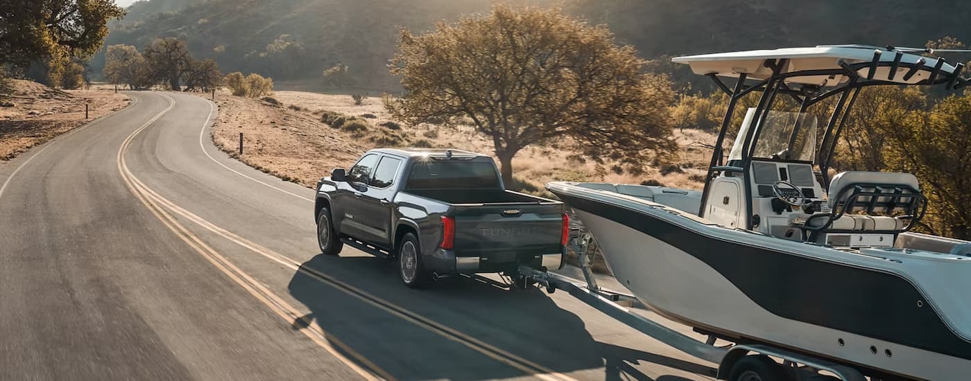 Black 2026 Toyota Tundra towing a boat on a winding road