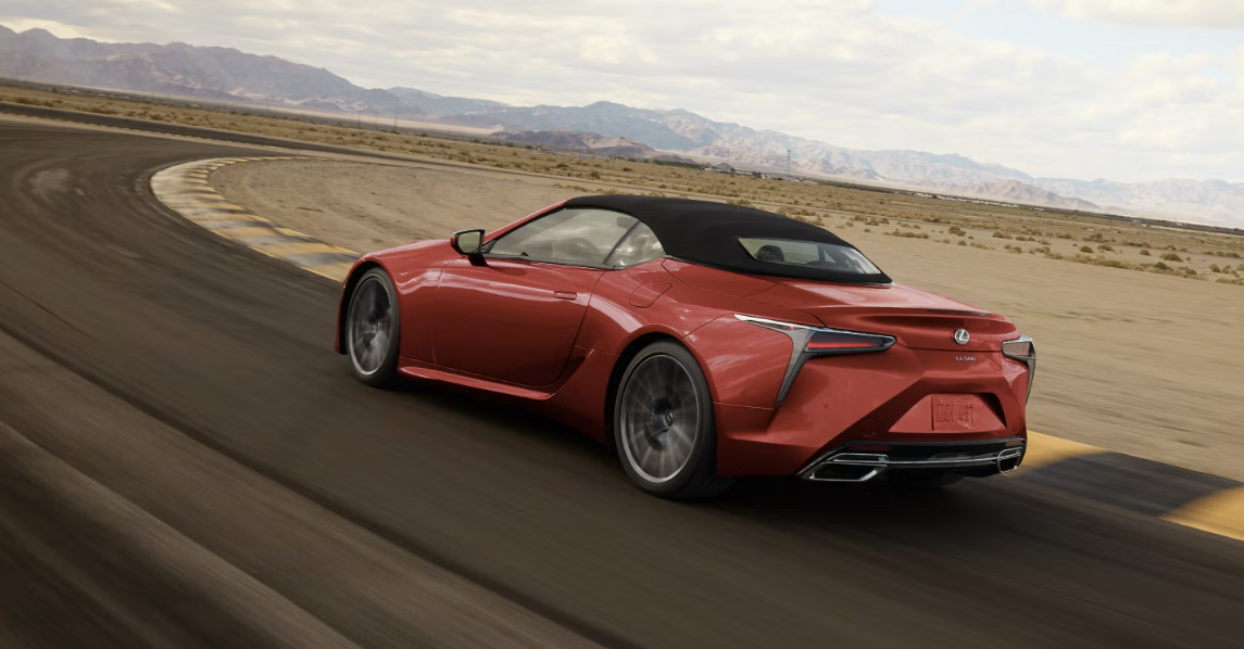 2026 Lexus LC 500 Convertible in red driving on a curved desert highway with the top up