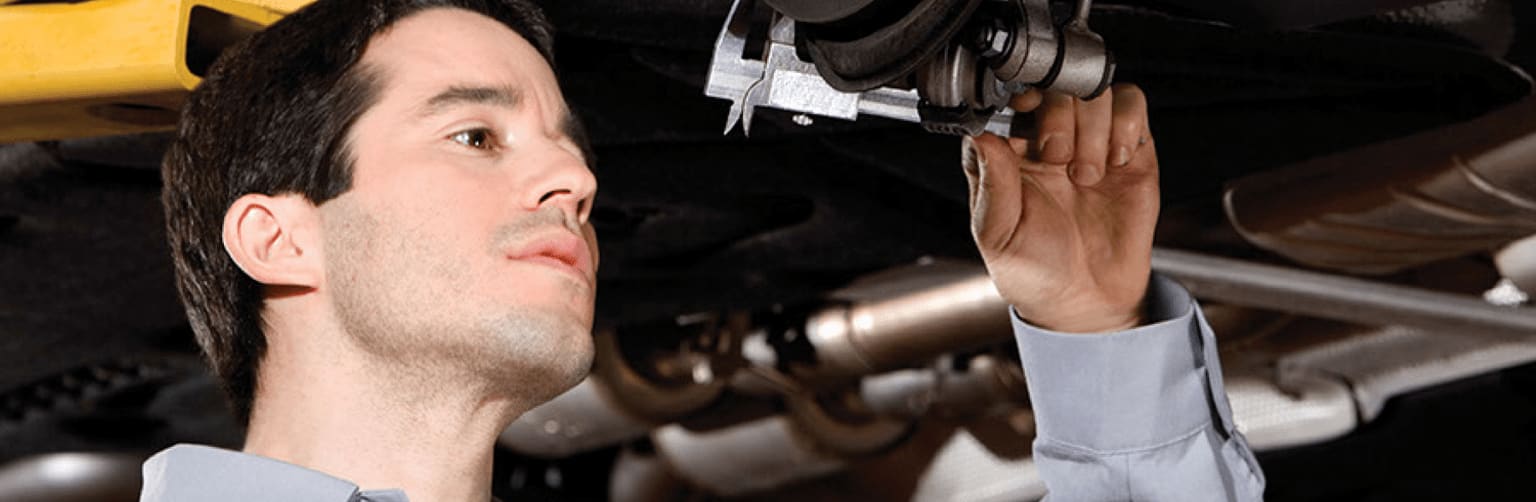 Man looks closely at a part on a Mercedes-Benz vehicle.