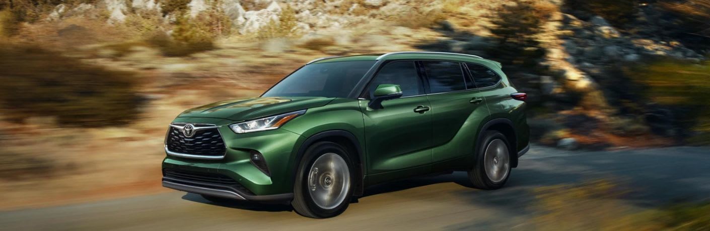 A green Toyota Highlander on the road. 