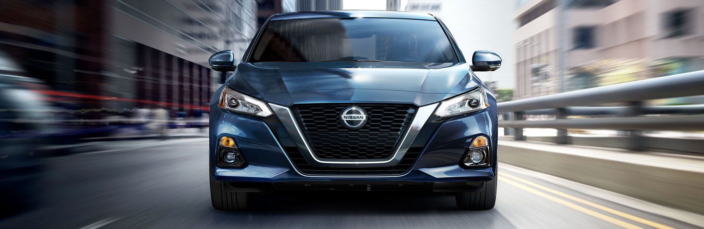 Head-on view of a 2020 Nissan Altima driving up a highway as the road blurs around it.