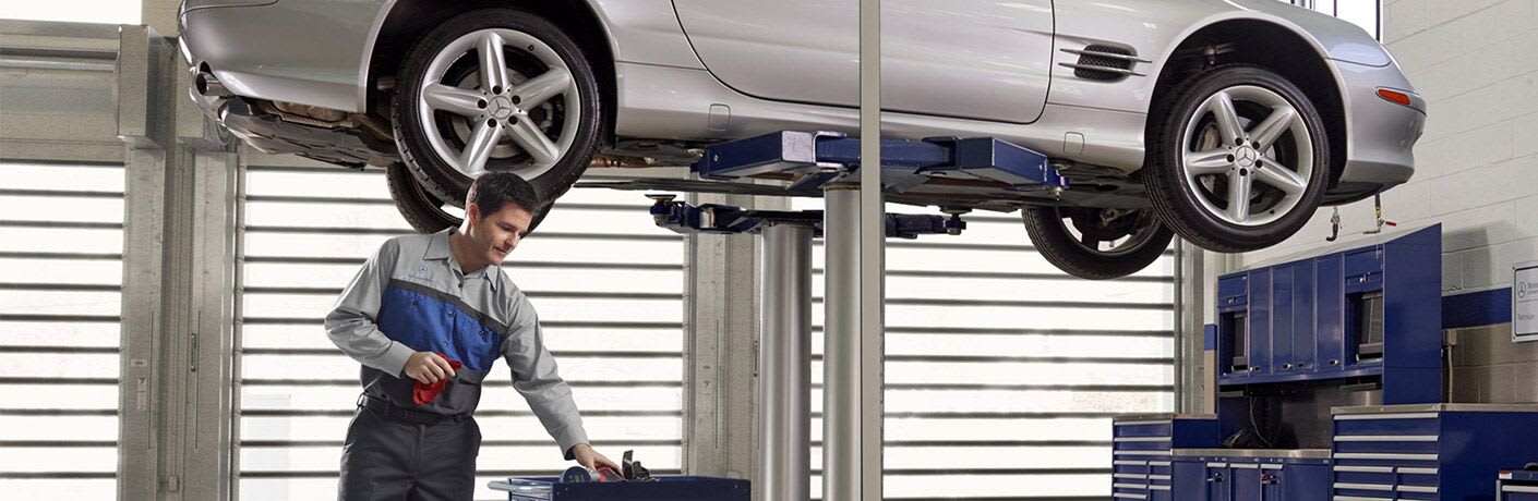 Mechanic prepares to work on a raised vehicle