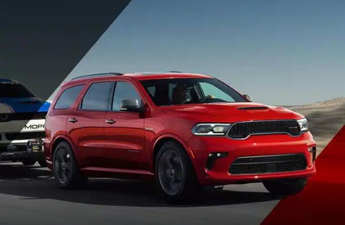 A red 2023 Dodge Durango towing a car.