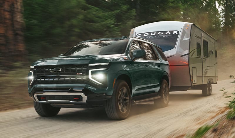 Green 2025 Chevrolet Tahoe towing a trailer