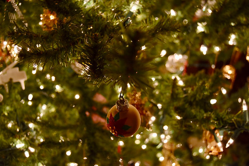 A Christmas tree ornament hanging on a Christmas Tree full of lights.