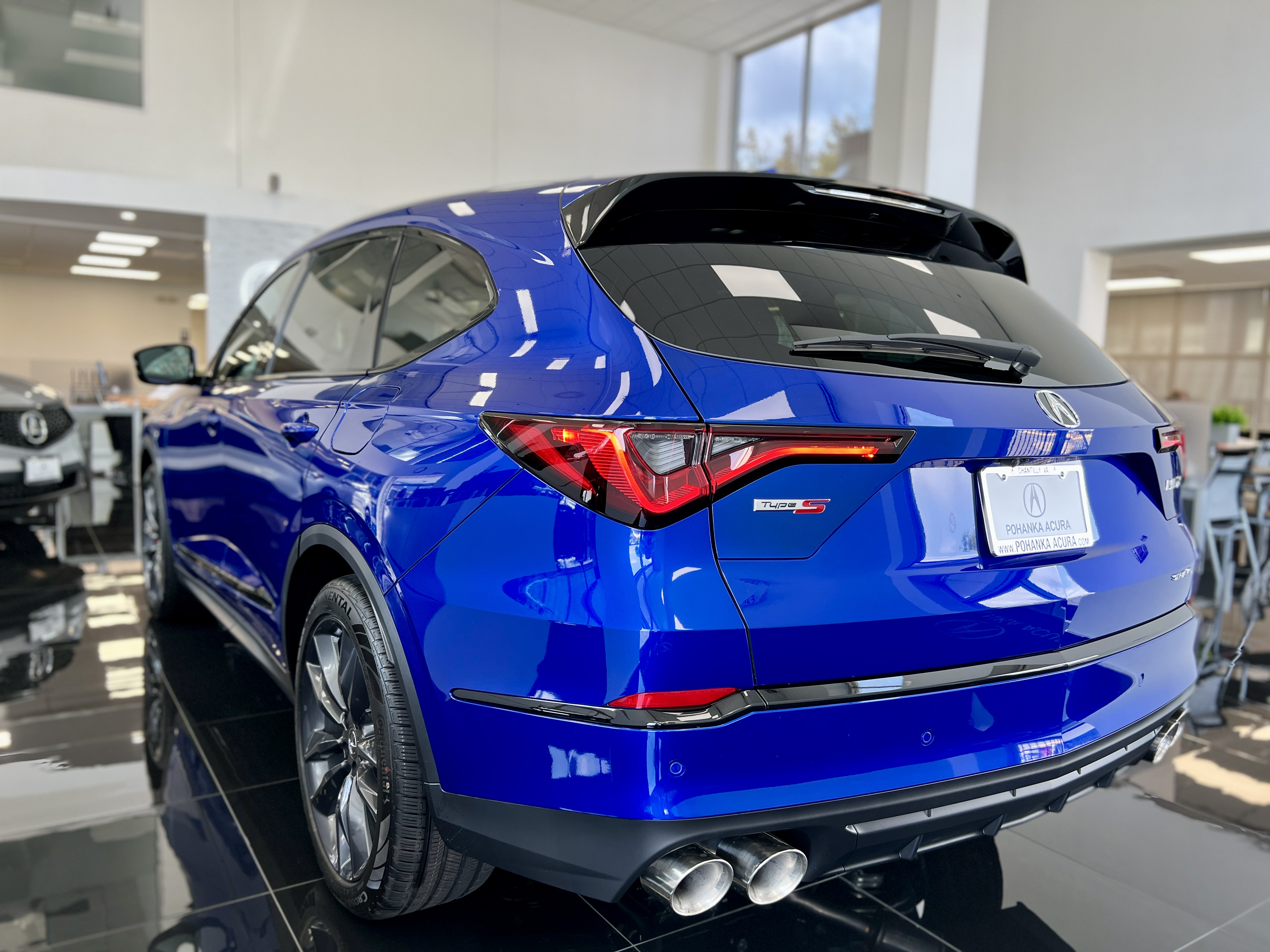 Rear and side view of blue Acura MDX in a showroom
