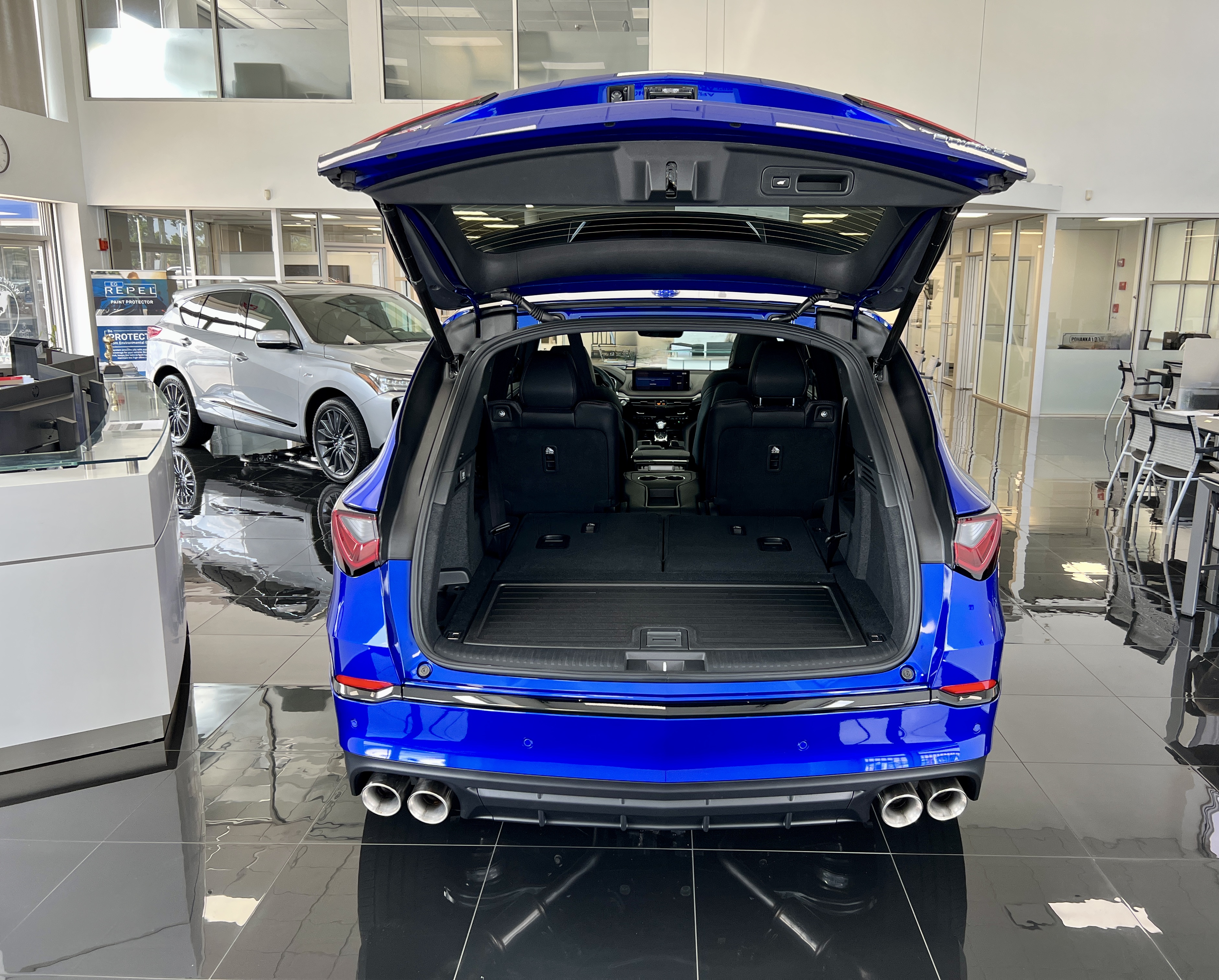 Rear view of blue acura mdx with hatch open and rear site folded down