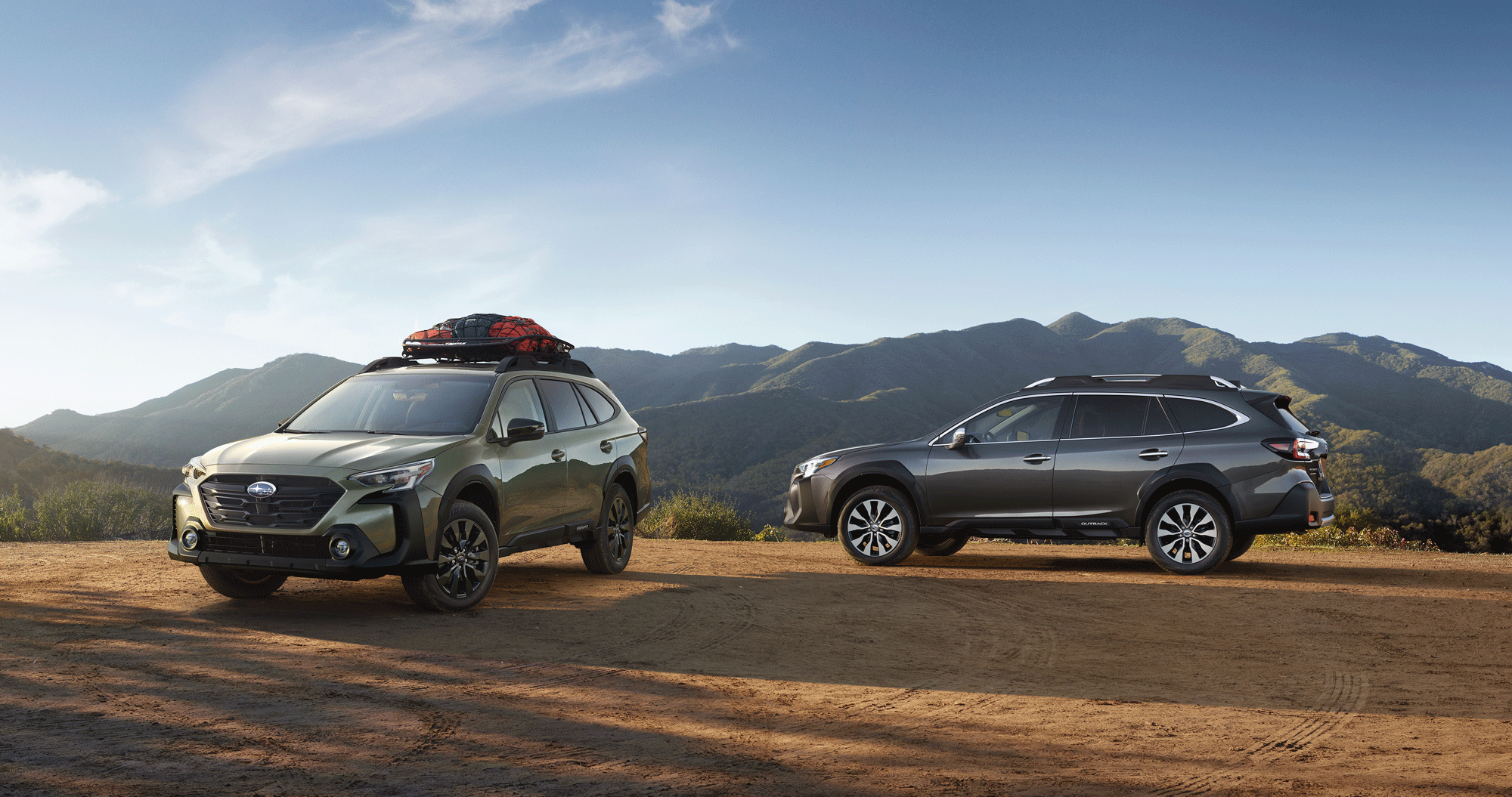 A pair of 2023 Outback vehicles parked in the mountains.
