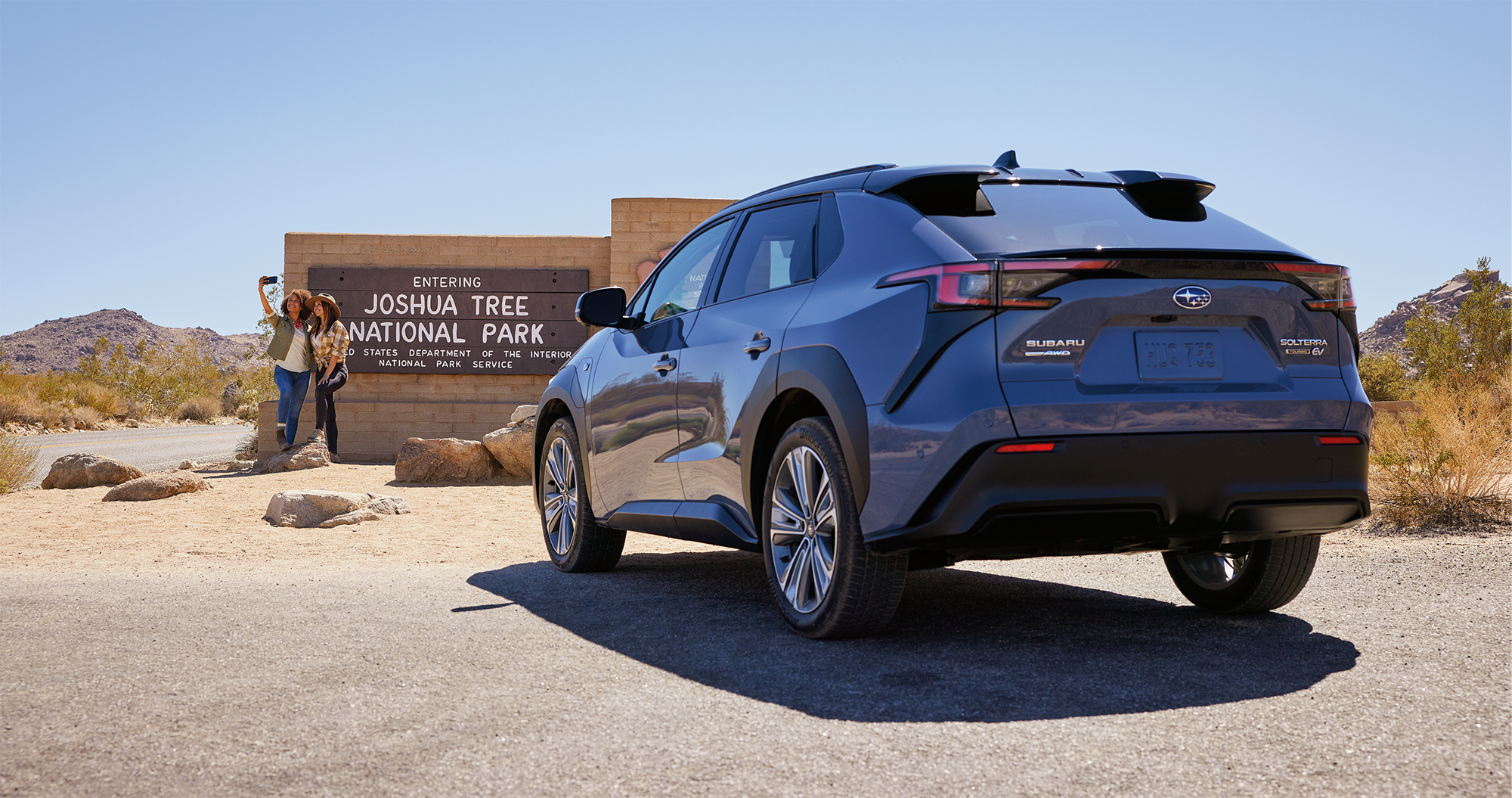 A couple taking a selfie at a national park sign near their 2023 Solterra.