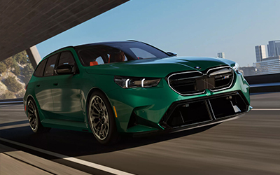 Green BMW M5 Touring driving on a city road.