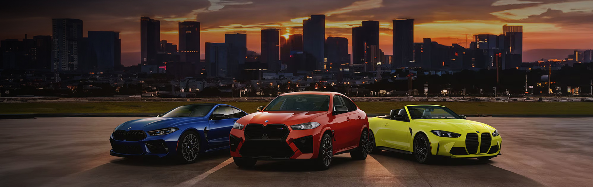 Colorful BMW M vehicles parked with a city skyline background.