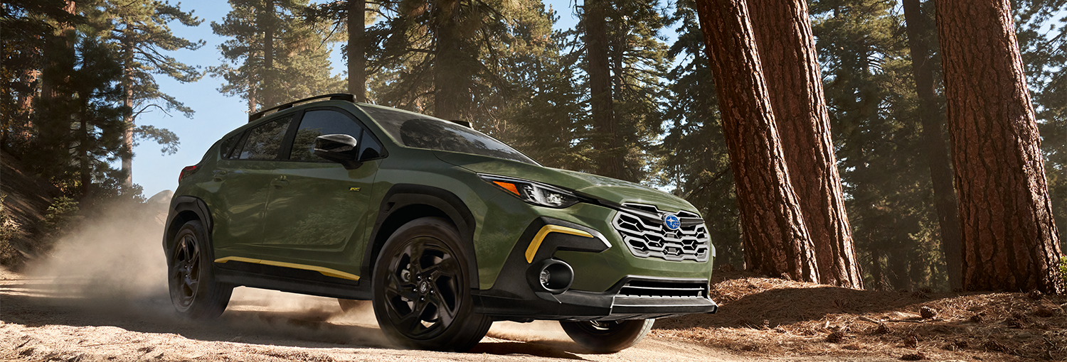 A 2025 Crosstrek Sport driving on a mountain road and through a forest.