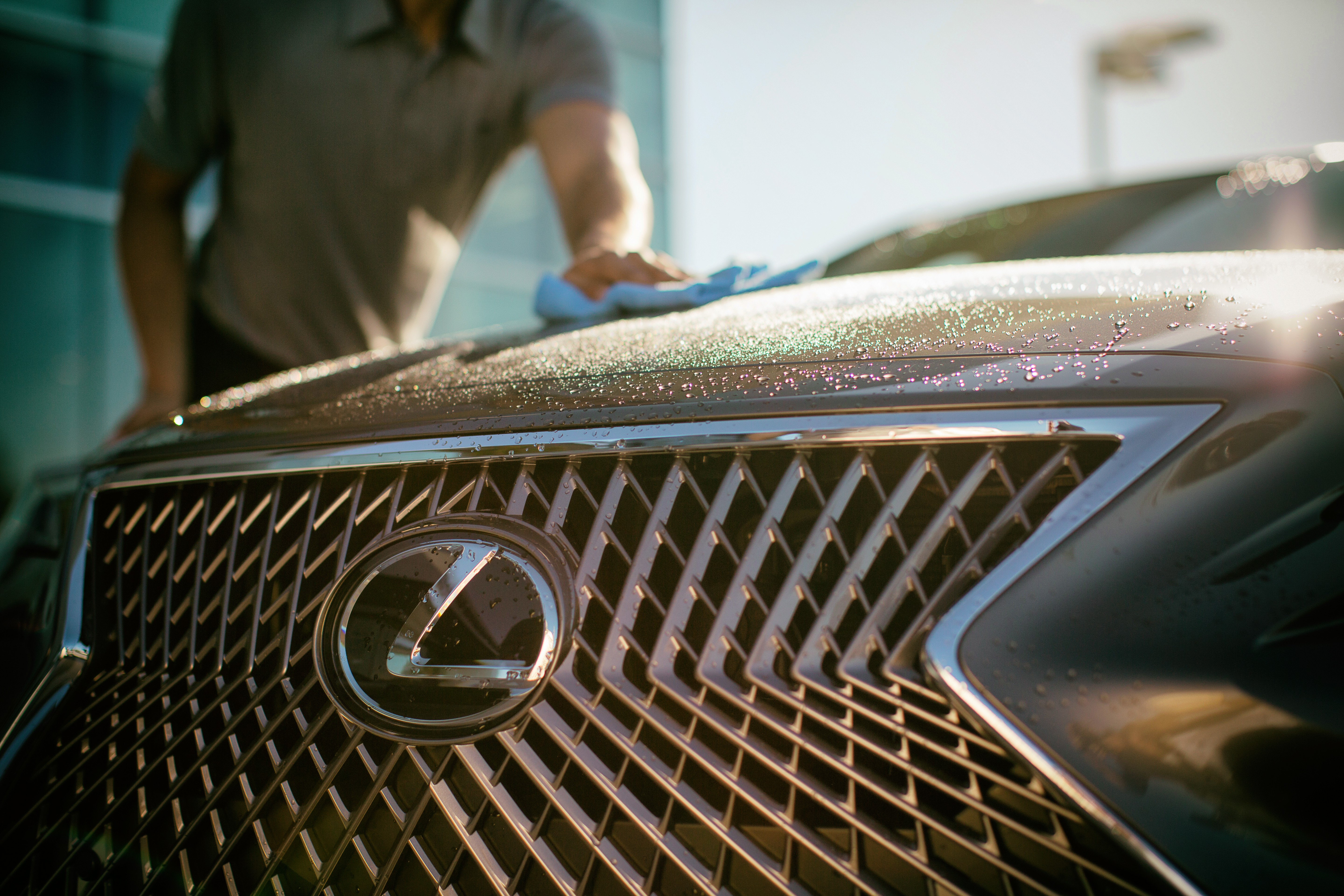 Man shown cleaning the hood of a Lexus vehicle.