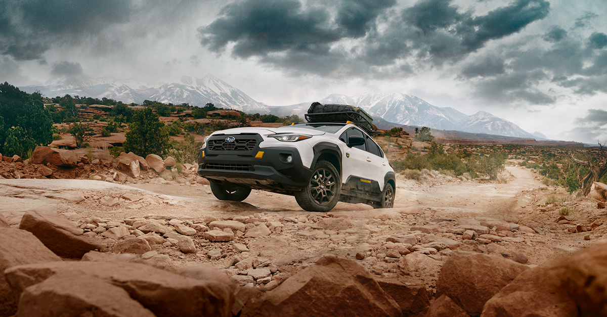 A white Crosstrek Wilderness drives up a rocky canyon