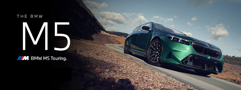 The BMW M5 Touring in green driving down desert road