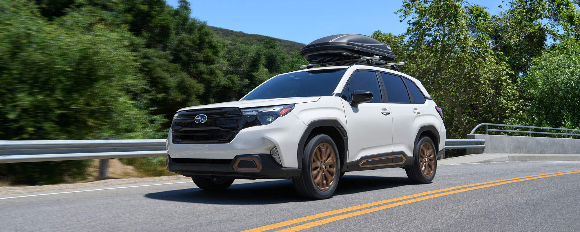 A 2026 Subaru Forester AWD SUV with a Thule storage attachment on its roof rails driving on a highway. 