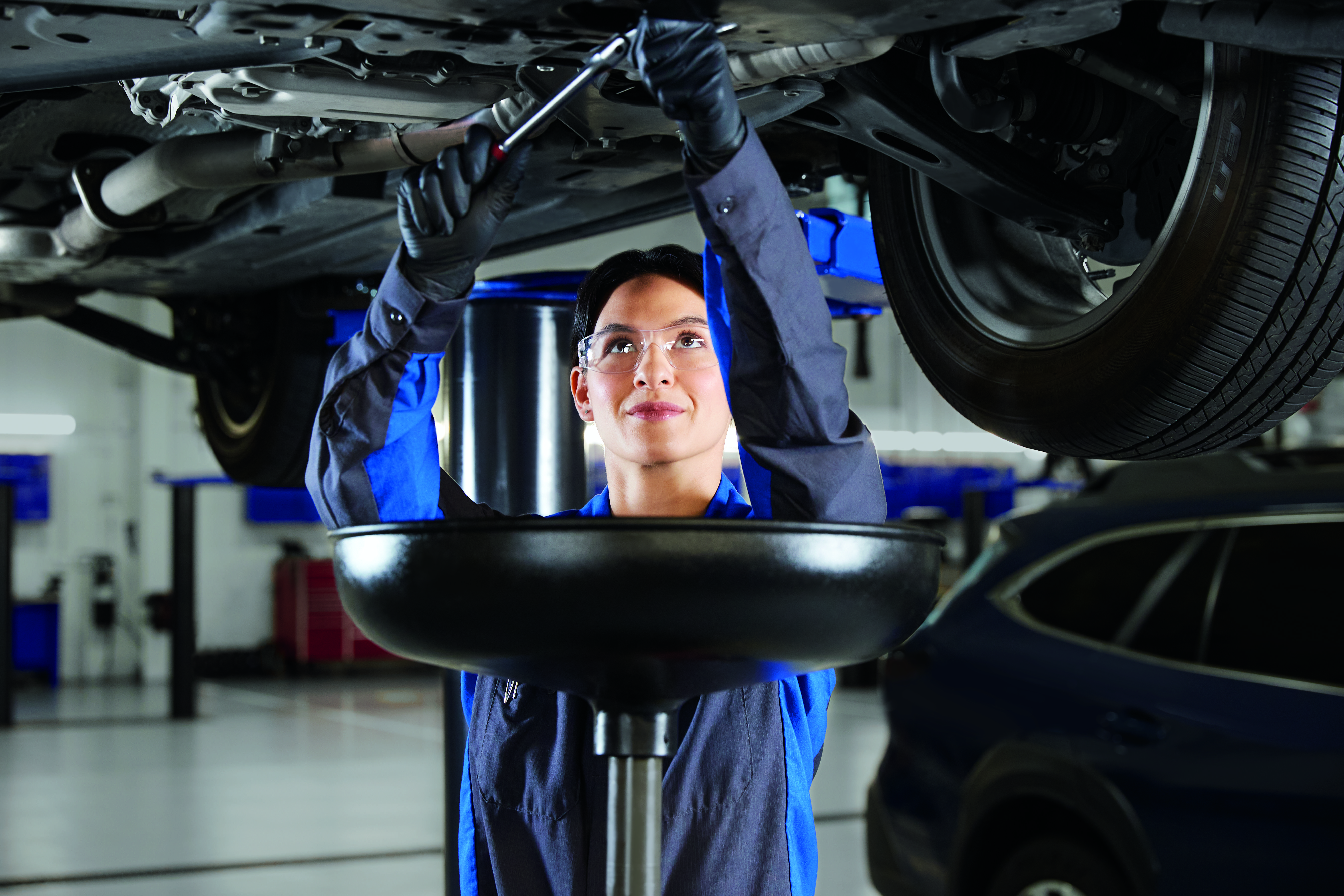 A Subaru service technician looking underneath a vehicle.