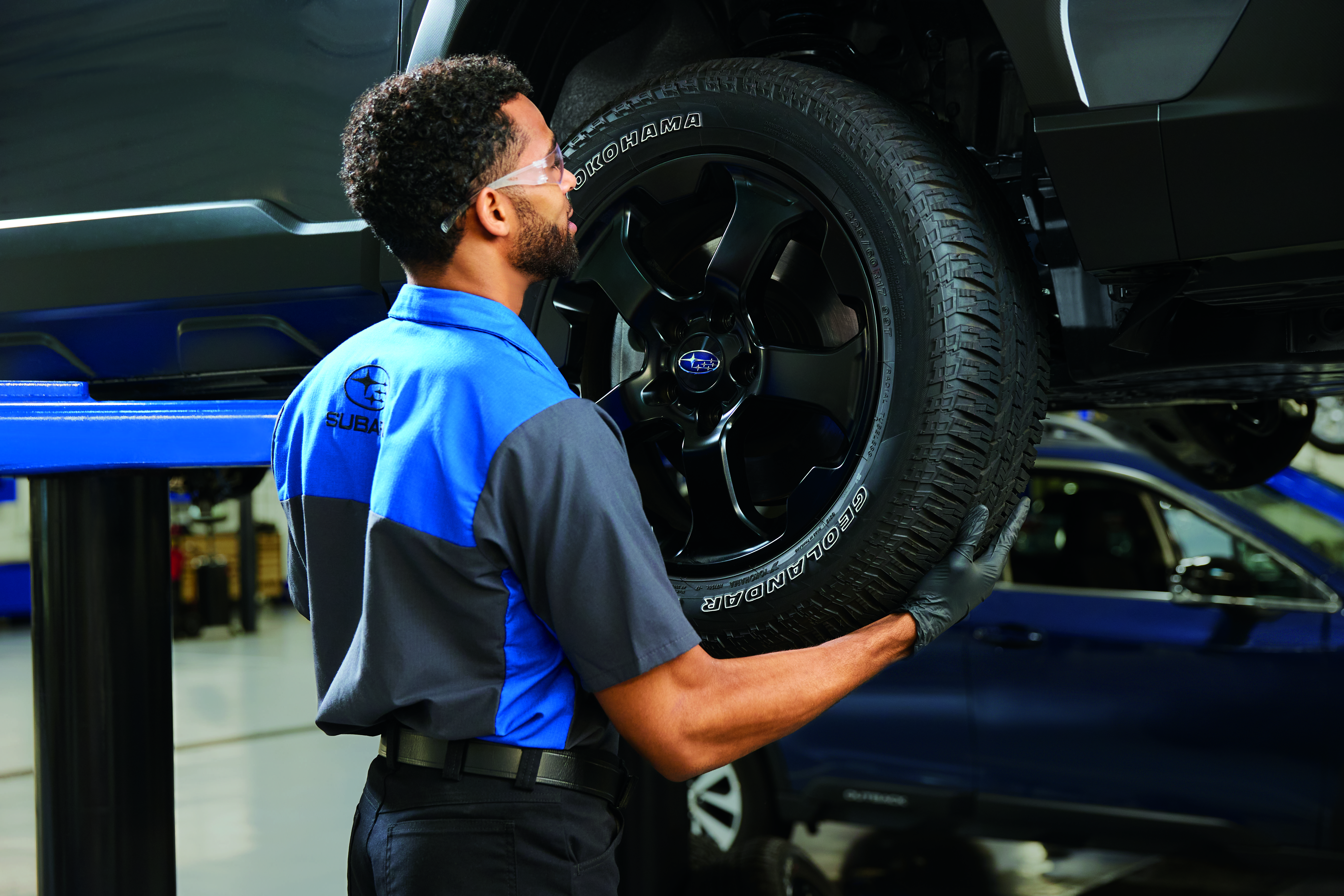 A Subaru service technician checking tires.
