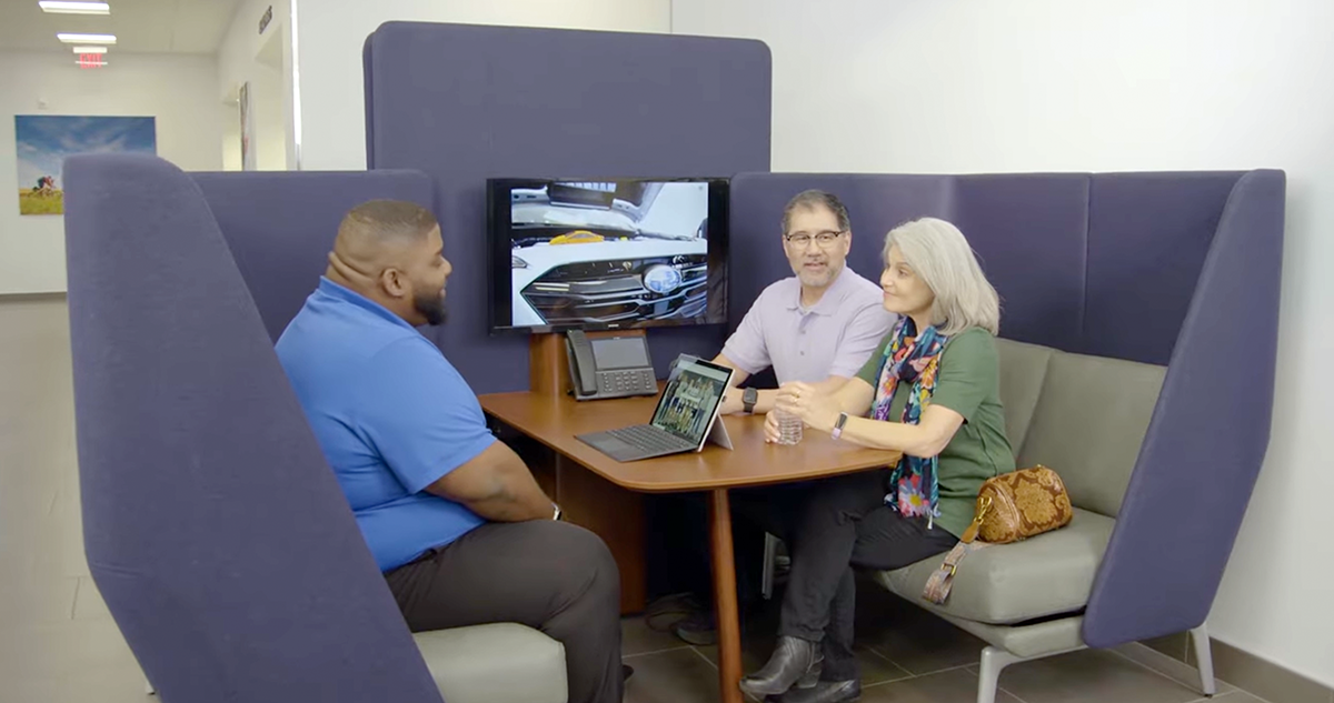 A Subaru Love-Encore delivery specialist talking with a couple of new Subaru owners about their vehicle's features.