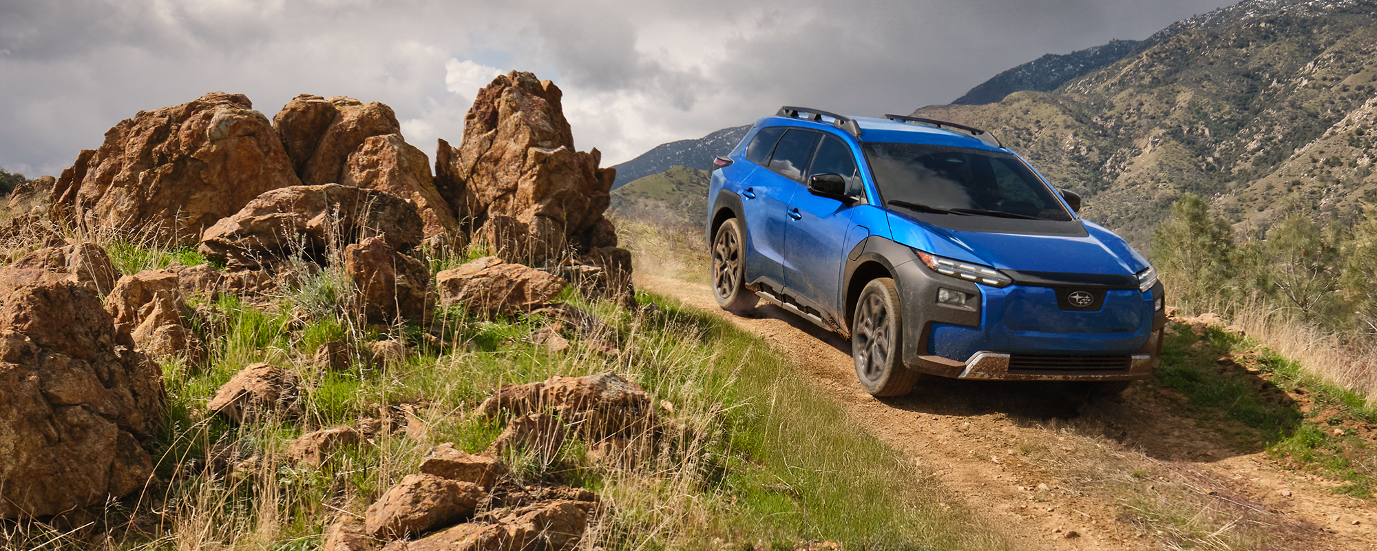 A 2026 Subaru Trailseeker in blue drives down an arid hill.
