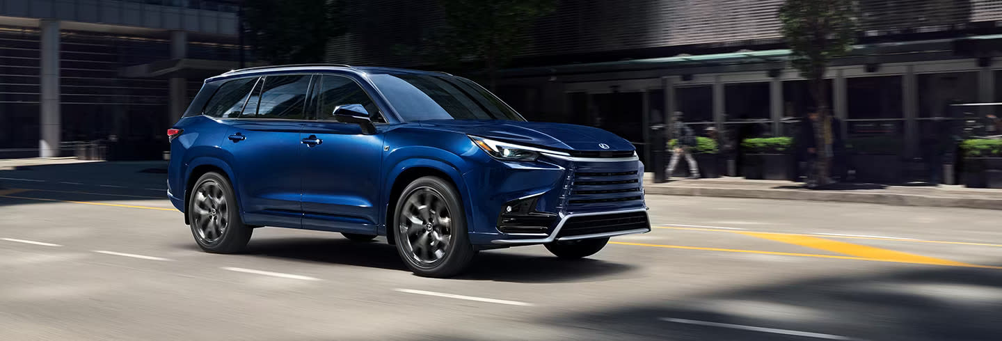 Passenger profile view of a blue Lexus TX driving on a city road