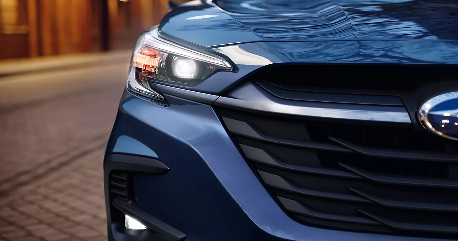 blue 2025 subaru legacy showcasing up close view of subaru emblem and grille