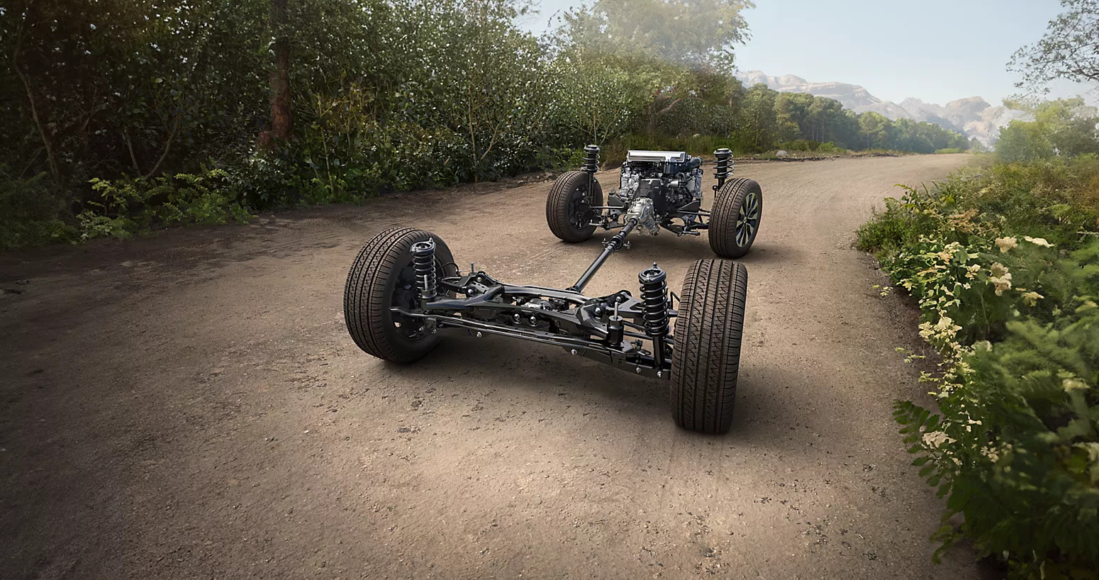 Subaru Outback chassis and symmetrical all-wheel drive components displayed on a dirt road, showcasing capability