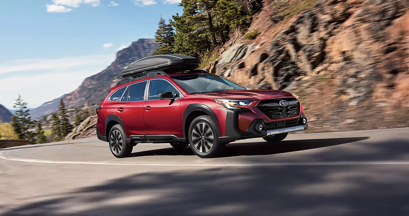 a red subaru outback driving up a mountain on a paved road