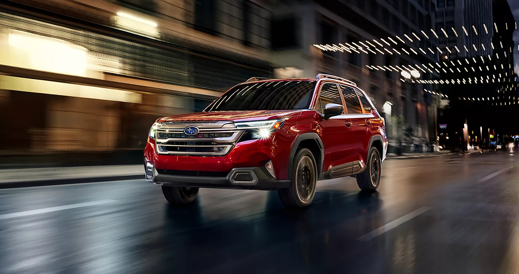 a red forester hybrid driving down a city road at night