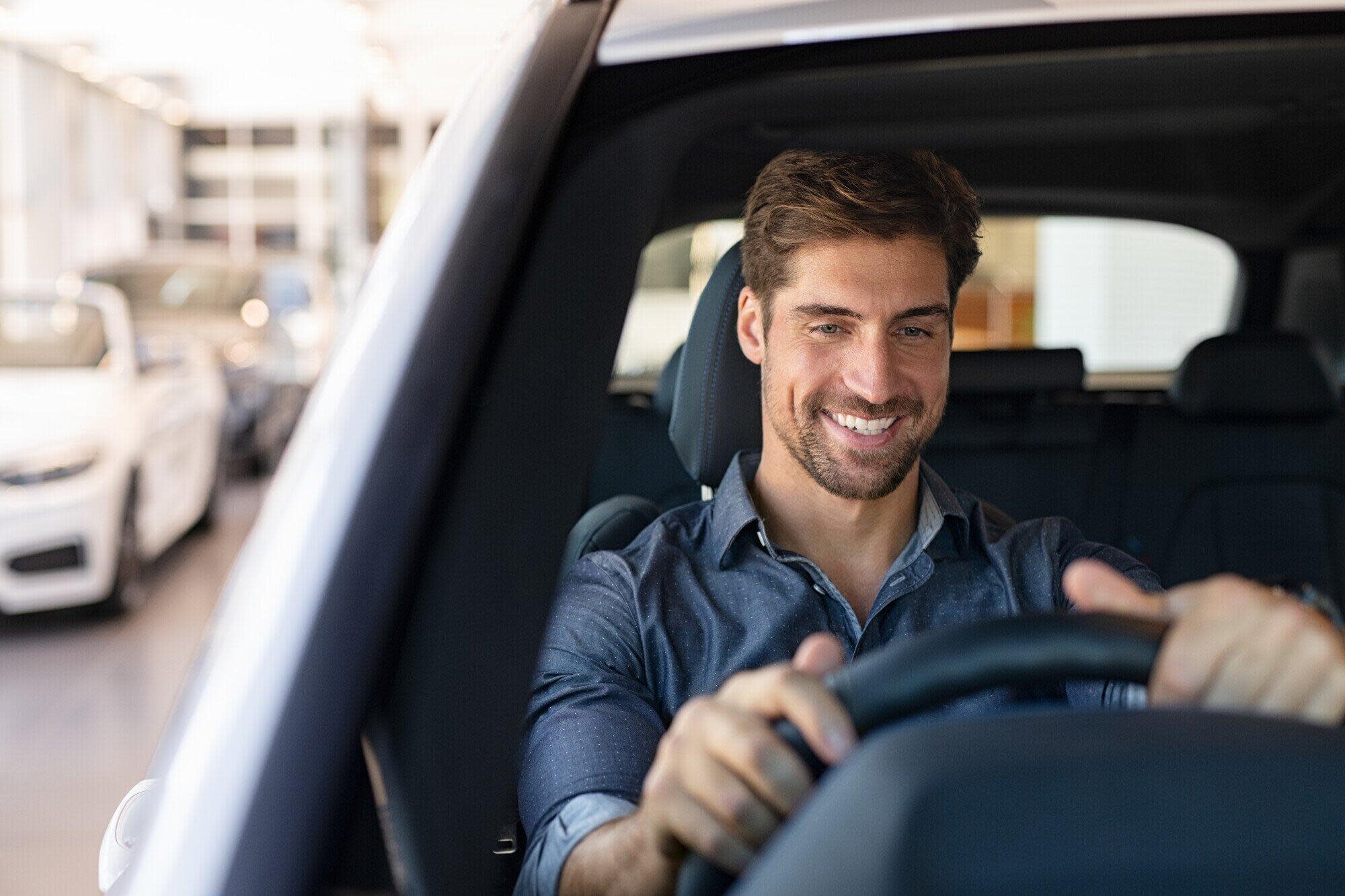 Young Smiling Man Examining A Car