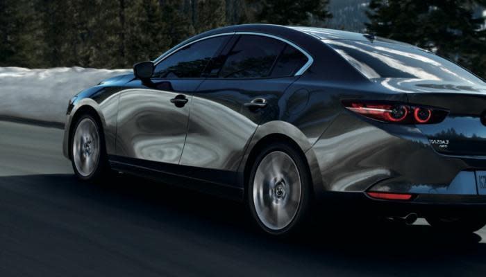 2021 Mazda3 Sedan driving down a city street.